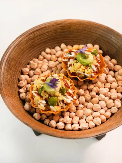 Our take on chaat, served in a crisp canapé shell over a bed of chickpeas. It’s a burst of tangy, sweet, and savoury flavours, finished with an edible flower for a touch of elegance.