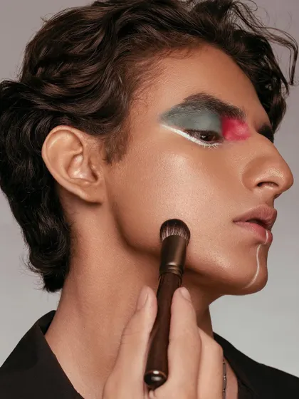 A profile view showing a makeup brush contouring the model's cheek. The focus is on the tool in action, demonstrating its function and precision. The artistic makeup adds a layer of creativity, positioning the brush as a professional-grade tool for any look.