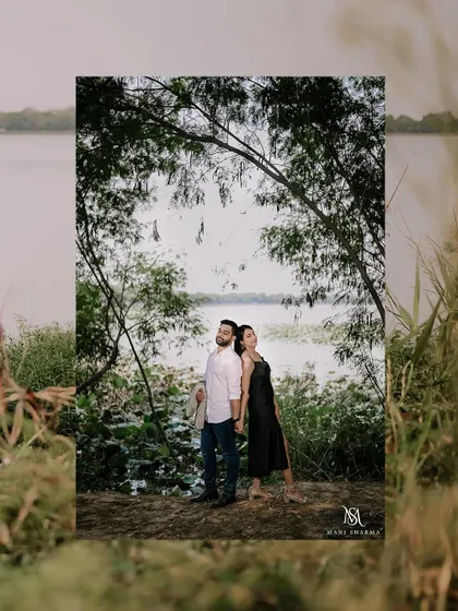 A beautifully framed shot of the couple by the water, using the natural foliage to create a sense of intimacy.