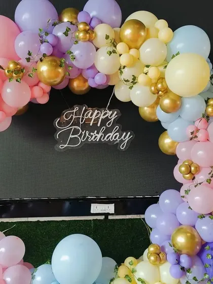 A close-up of the beautiful pastel rainbow balloon arch, accented with gold balloons and green leaves.