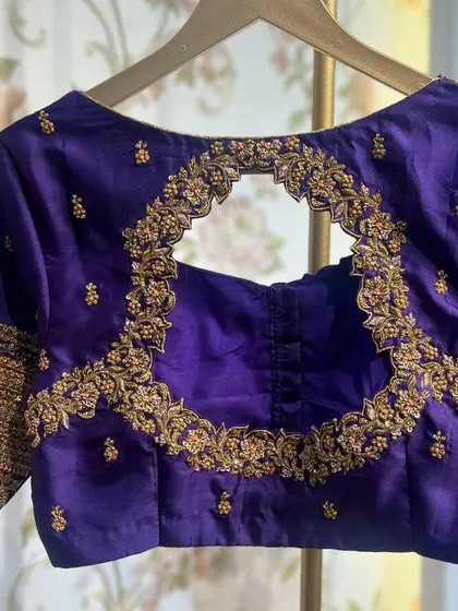 The back of the purple blouse, featuring a circular cut-out framed with detailed embroidery.