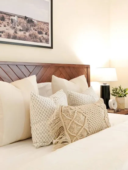 The master bedroom in my JWD Marq Home is a tone-on-tone retreat. I layered various textures and patterns in neutral shades, from the macrame pillow to the chevron-patterned wood headboard, to create a space that feels elevated and serene.