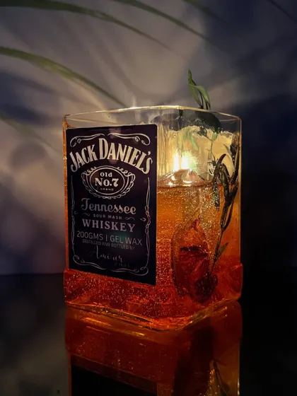Another angle of the lit Jack Daniels candle, highlighting the sparkling gel wax and the rustic botanicals inside.