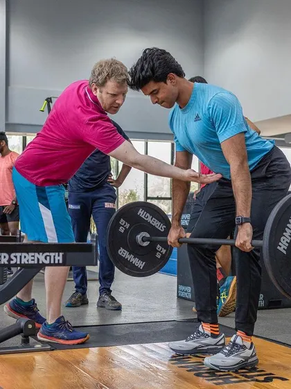 A UKSCA assessor corrects a trainee's deadlift form, emphasizing the importance of proper mechanics for safety and effectiveness.