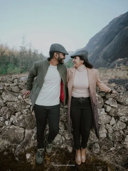 Ananthu and Sarga sharing a happy glance during their mountain shoot. Their coordinated vintage outfits and the rugged landscape create a unique, story-driven visual.