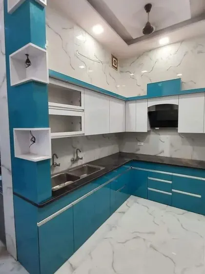 This two-tone kitchen in blue and white features a unique pillar with built-in display shelves. The marble-patterned walls and floor add a touch of luxury.