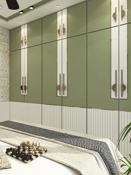 This bedroom design uses a calming sage green on the wardrobe, accented with white panels and unique handles. The lower half of the wall features white fluted paneling, adding texture and a modern touch.