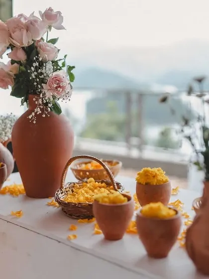 A close-up of the beautiful, rustic decor. The combination of earthy terracotta, delicate pink roses, and scattered marigold petals created a simple yet elegant aesthetic.