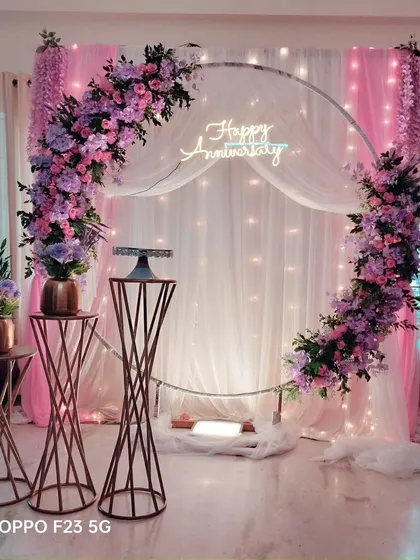 A simple and customized anniversary decoration featuring a floral ring in shades of pink and purple. The setup is perfect for an intimate celebration at home.