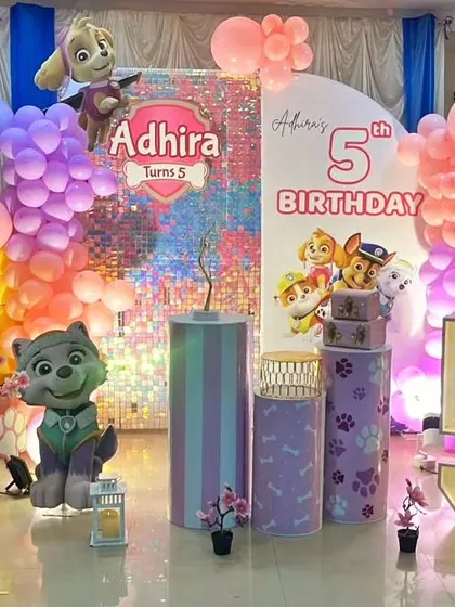 This Paw Patrol party for a 5th birthday combines a shimmering sequin backdrop with character cutouts of Skye and Everest. The pastel and rainbow color scheme gives it a unique, vibrant look.