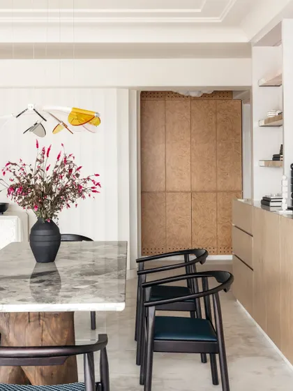 The dining area flows seamlessly from the entrance, with soft, raw cotton hues on the walls creating a calming backdrop. Pops of color and subtle accents reflect the personalities of the family members.