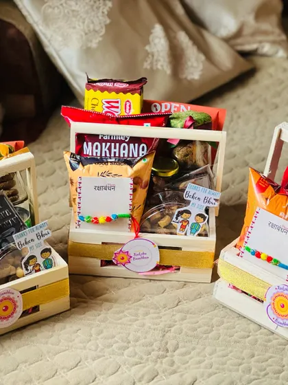 Small wooden crate hampers for Rakhi, filled with snacks and decorated with cute "Behen Bhai" stickers.