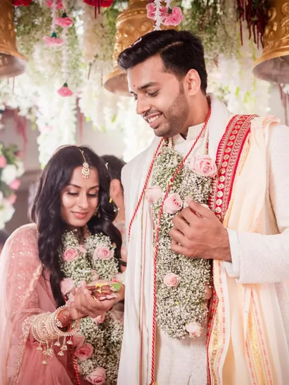 A tender moment during the wedding ceremony. The couple's expressions are full of love and reverence as they participate in a ritual together.