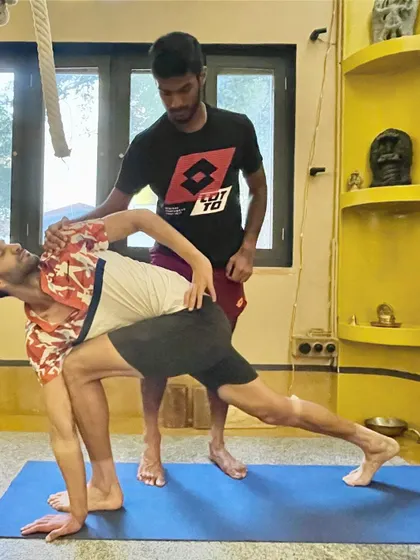 Assisting a player in a deep side lunge (Parsvakonasana variation). This pose stretches the entire side body, opens the hips, and strengthens the legs, all of which are vital for the dynamic movements in tennis.