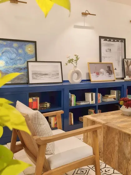 Another view of the custom blue bookcase, showcasing how my clients' art collection is thoughtfully displayed. The picture lights above highlight each piece, turning the wall into a personal gallery.