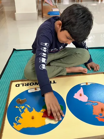 A child explores a world map puzzle, a hands-on tool that brings geography to life.