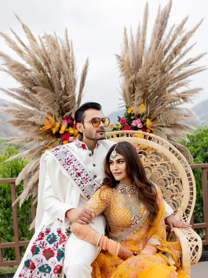 A stylish portrait of the couple from their Mehendi ceremony. The bohemian-chic decor with pampas grass complements their modern-traditional outfits perfectly.