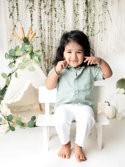 Such a cute and shy expression from this little boy. The natural elements like the greenery and pumpkins add a lovely touch to this bohemian-inspired setup.