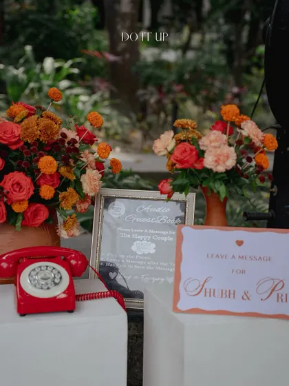 A unique guest book idea for the Rishikesh Haldi. A vintage red telephone is set up for guests to leave audio messages for the couple, combining a nostalgic touch with modern technology.