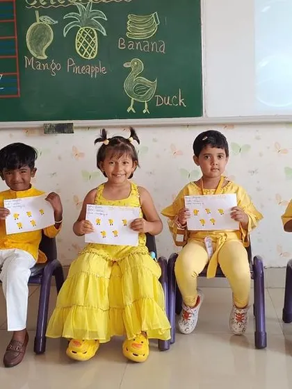 Students hold up their artwork from the Yellow Day celebration, showcasing their creativity and learning.