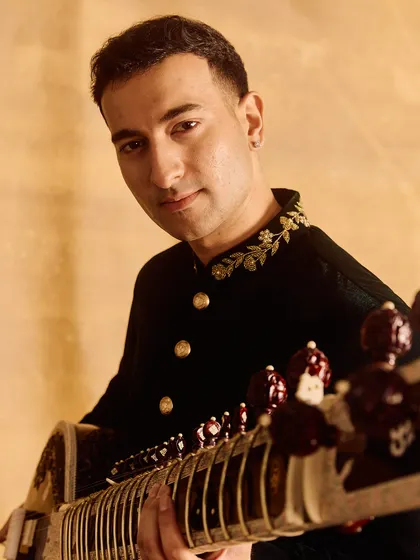 A close-up portrait focusing on the details of the outfit and the sitar.