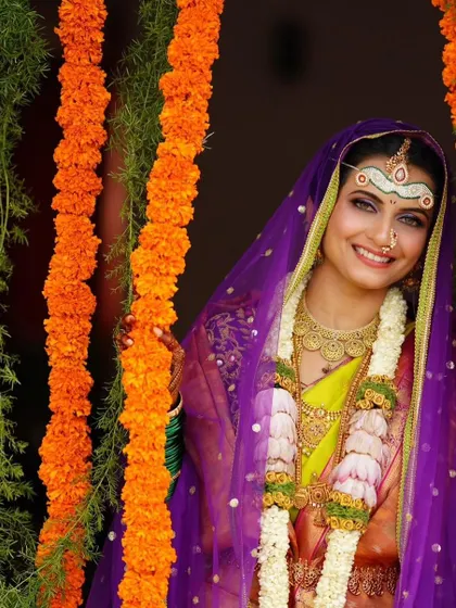 The bride's smile shines through the traditional veil. The makeup is bright and joyful, with a focus on her expressive eyes.