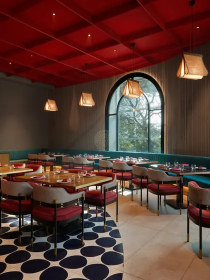 The geometric floor pattern curves through the space, defining the walkway and adding a dynamic visual element that contrasts with the solid red ceiling.