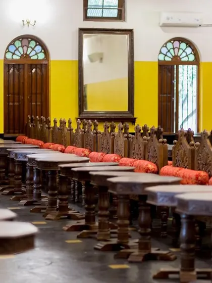 The dining hall, set up with traditional wooden stools for a sadhya feast or other traditional meals.