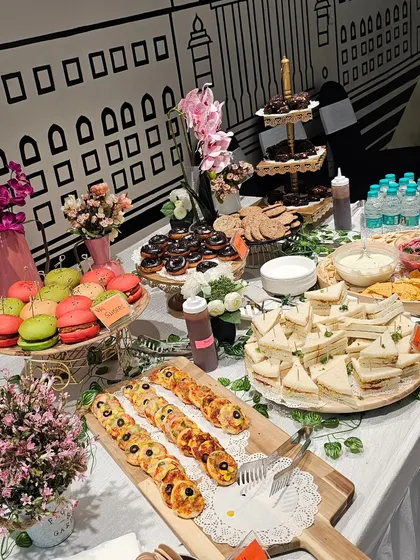 Another angle of our beautiful hi-tea setup, showcasing the variety of sweet and savory items. The arrangement includes mini pizzas, sandwiches, macarons, and donuts.