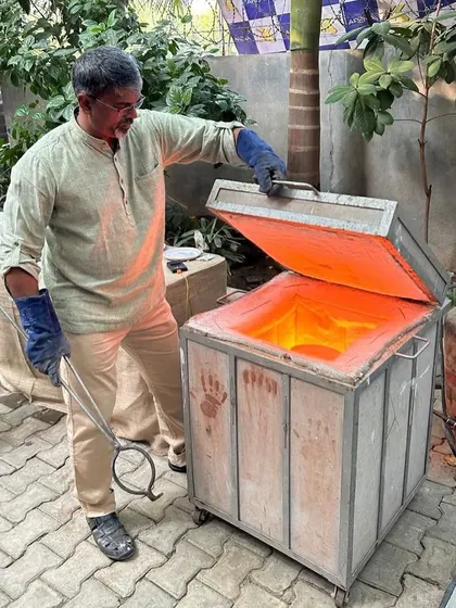 I am opening the glowing hot Raku kiln, ready to remove the pottery. This is a critical moment in the dramatic and fast-paced firing process.