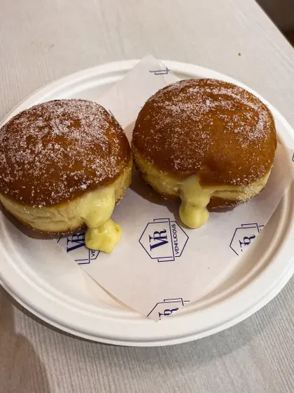 A pair of our Custard Berliners, fresh from the kitchen. The cream gently oozes out, promising a delicious bite.
