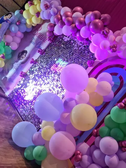 A closer view of a princess-themed party, showing the pastel balloon decorations and the sequin wall that creates a sparkling effect.