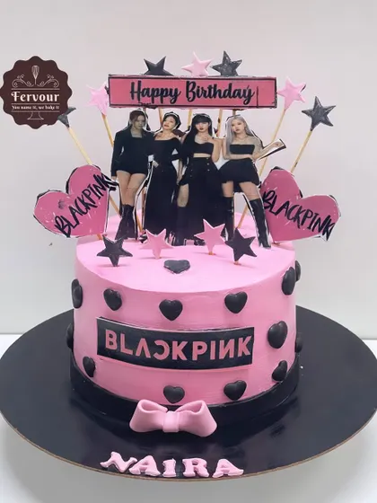 A Blackpink-themed cake for a K-pop fan. The pink and black design features the group's logo, an edible image of the members, and star decorations.