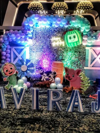 The main stage of the Cocomelon party, featuring a silver sequin backdrop that adds a touch of sparkle to the farm animal theme.