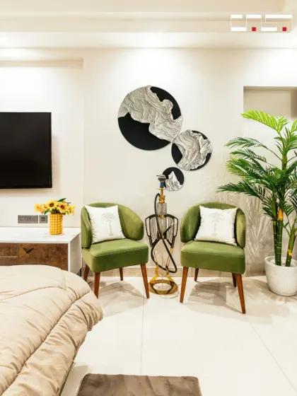 A cozy seating nook within a bedroom, featuring two olive green armchairs and unique wall art. This little corner is perfect for reading or enjoying a quiet moment.