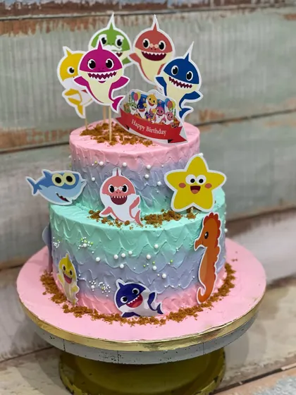This two-tiered Baby Shark cake was so much fun to make for a little one's birthday. The colorful buttercream and cute character toppers brought the underwater theme to life.