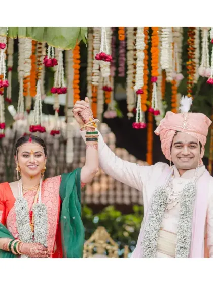 Just married! The couple raises their hands in celebration after a traditional Marathi wedding ritual. Their joyful expressions are a testament to a beautiful ceremony.