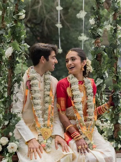 A beautiful NRI couple on the swing, blending Telugu and North Indian traditions in their attire and creating a joyful, vibrant image.