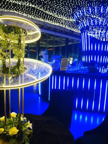 A modern floral centerpiece with an integrated light fixture, set against the glowing blue bar, showcasing our blend of contemporary design and classic elements.