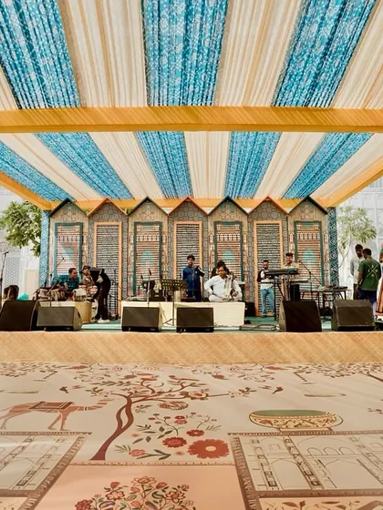 The stage for the live band, set against a backdrop of traditional Rajasthani architectural motifs. The custom-printed dance floor features designs inspired by local flora and fauna.