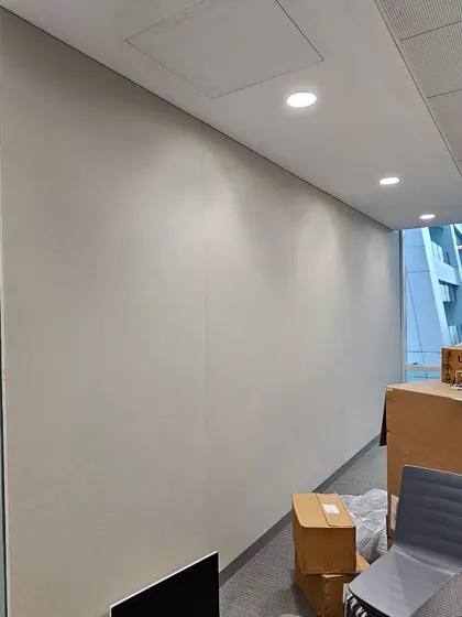 This shows a long wall in an office being treated with acoustic fabric. This is a common solution to reduce echo and noise travel in hallways and large open spaces.