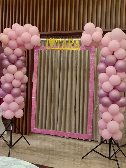 To complement a naming ceremony, I can create fun additions like this custom selfie booth. It provides a great spot for guests to take memorable photos, framed by balloon columns matching the event's color scheme.