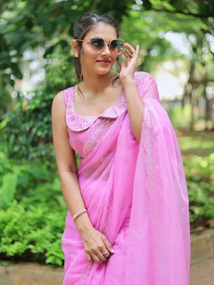 A model looking chic in a pink organza saree with a unique collared blouse design. This is a great example of how I can customize blouses to create a modern look.