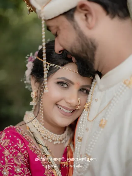 A beautiful close-up portrait of the bride looking at the camera while embracing her groom, with a romantic Marathi quote.