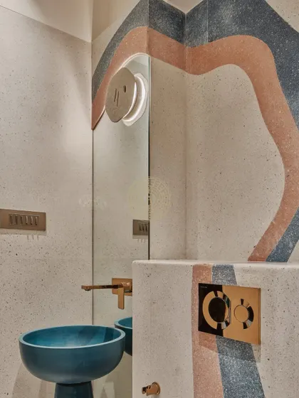 Another angle of the kids' bathroom, highlighting the custom terrazzo pattern and the unique blue basin. The brass fixtures add a touch of warmth and sophistication to the playful design.