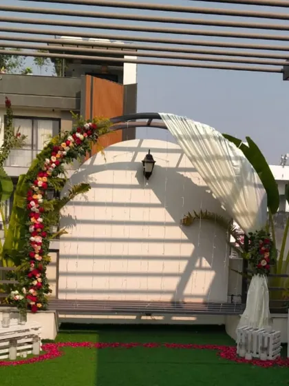 A daytime view of the complete terrace setup, showing the arch with draped fabric and floral arrangements ready for an evening surprise.