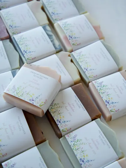A beautiful array of 60 handmade soaps, each with a custom floral label designed for a client's baby shower. This image captures the variety and personalized touch I bring to bulk orders for special events.