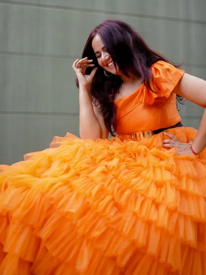 A seated portrait in the orange ruffle gown, showing the incredible volume and texture of the skirt.