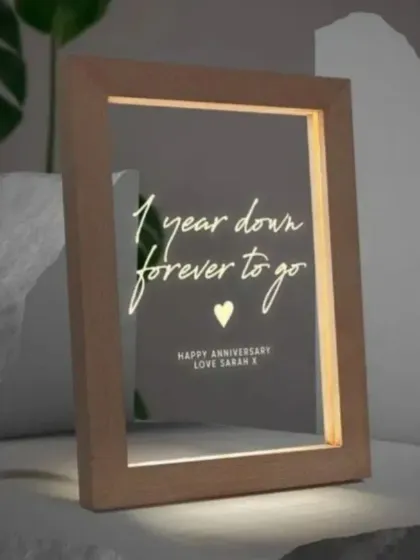 An elegant LED photo frame with a custom message, perfect for an anniversary. The message "1 year down, forever to go" is beautifully lit from within the frame.