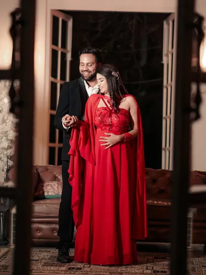 A classic pre-wedding portrait. The bride-to-be wears a stunning red gown, and her makeup is glamorous with a defined eye and radiant skin, perfect for this romantic indoor shot.